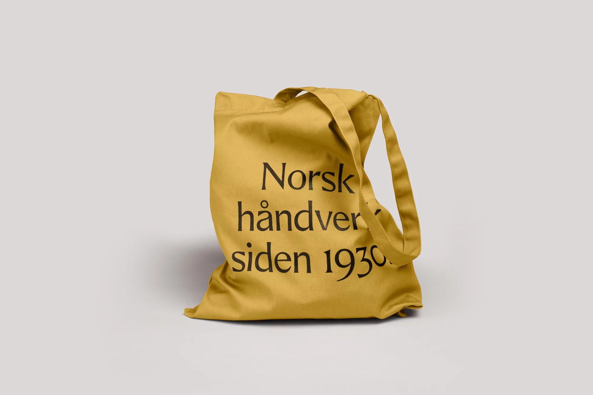 Yellow cotton tote bag with black printed text against a neutral background for product advertising or brand promotion.