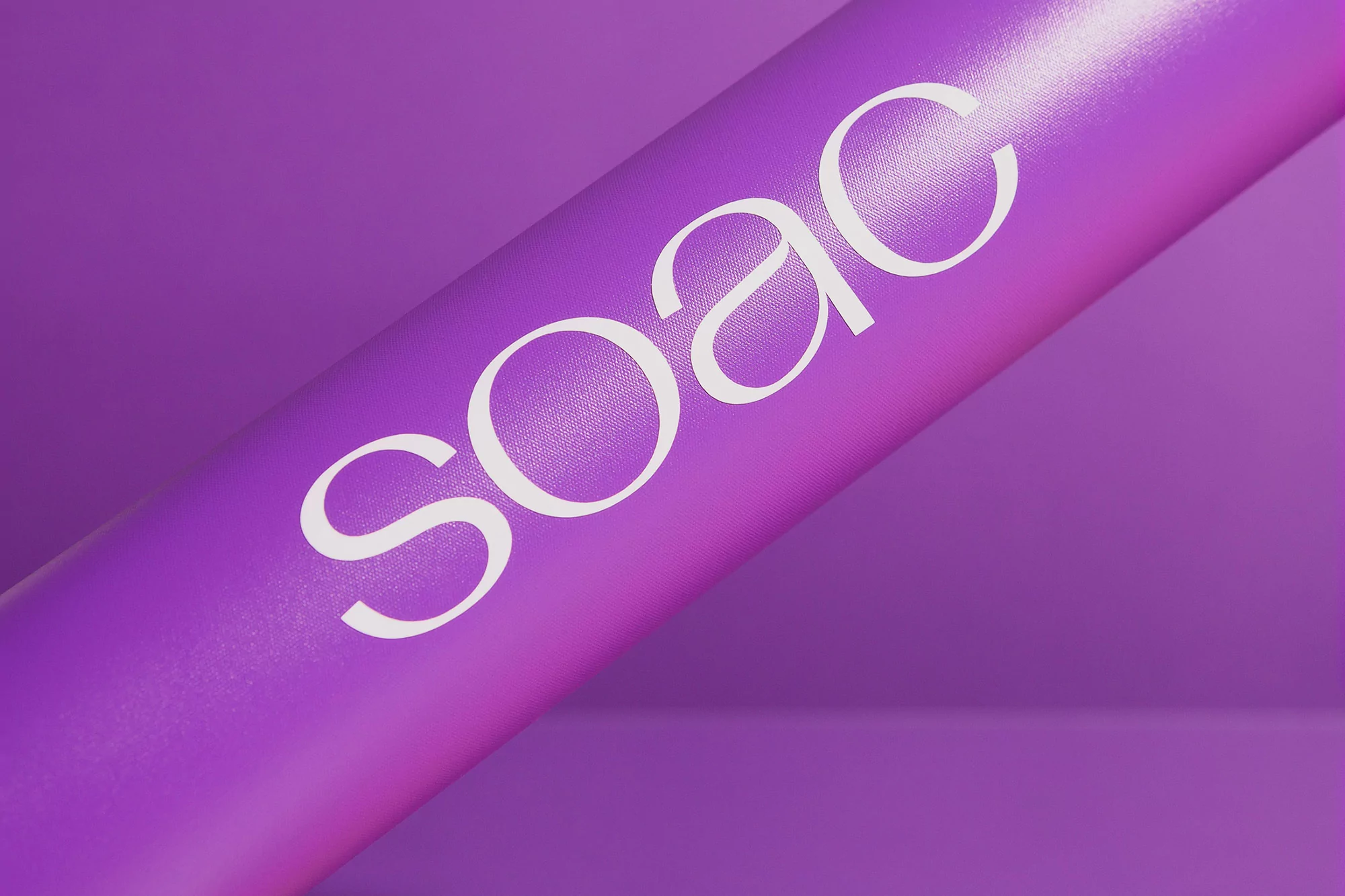 Purple background with a cylindrical object displaying 'SOAC' in white font, creating a modern and minimalist visual.