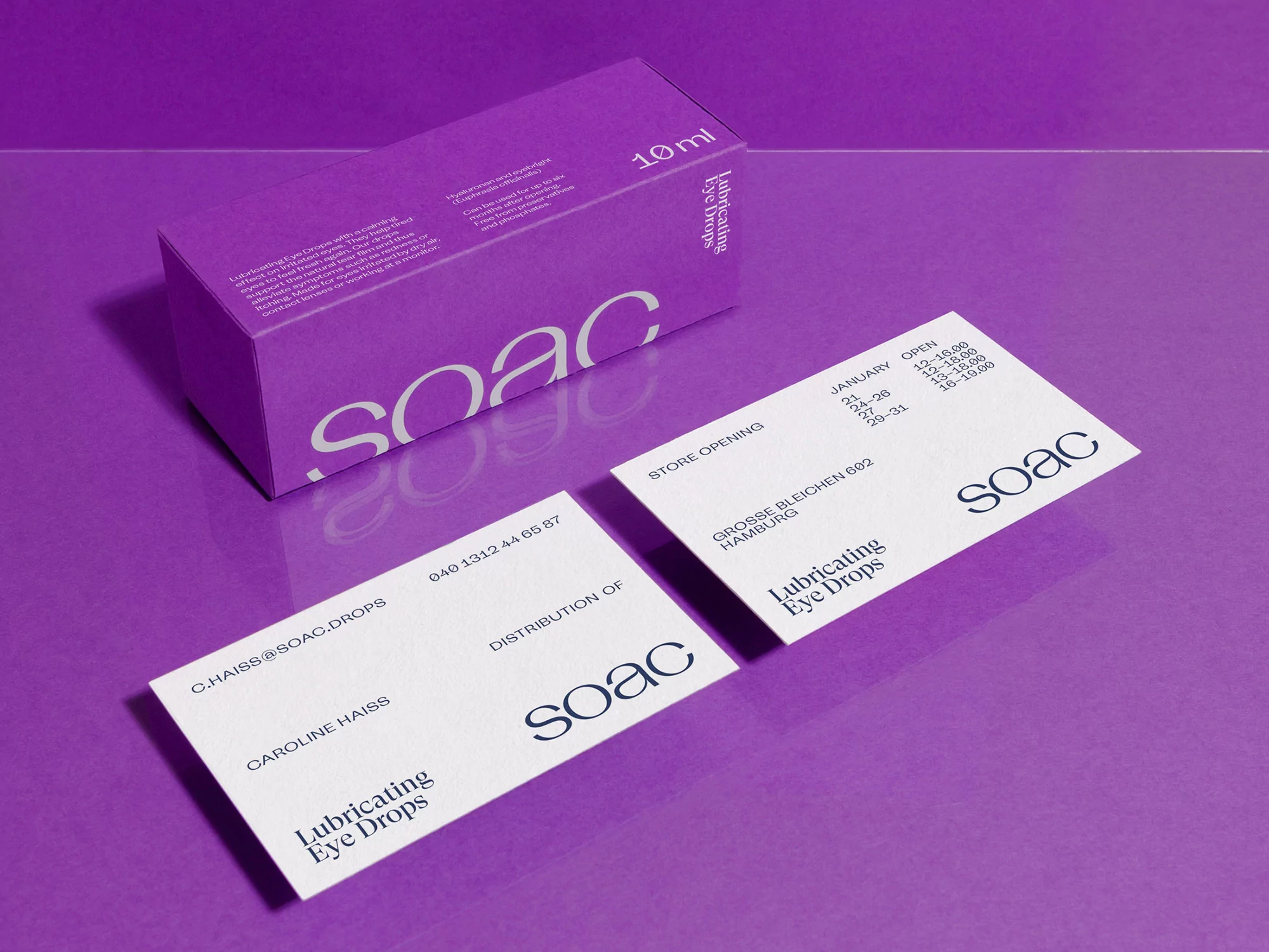 Close-up of a skincare product box and business cards on a purple surface showcasing branding, packaging, and product details.