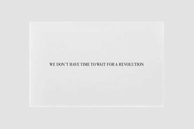Black text on a white surface stating, 'WE DON'T HAVE TIME TO WAIT FOR A REVOLUTION,' emphasizing urgency and proactive change.