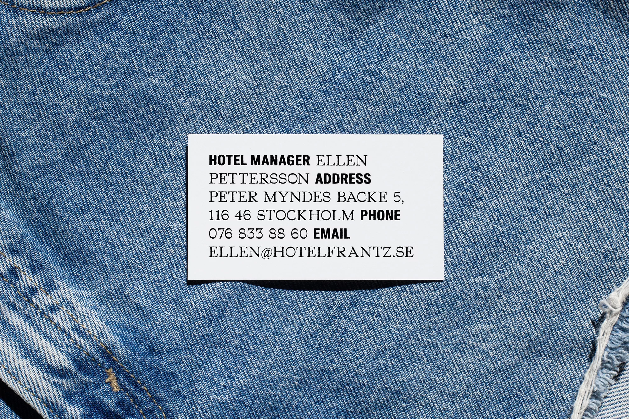 Business card of Ellen Pettersson, a hotel manager in Stockholm, Sweden, rests on blue denim fabric with a clear, professional design.