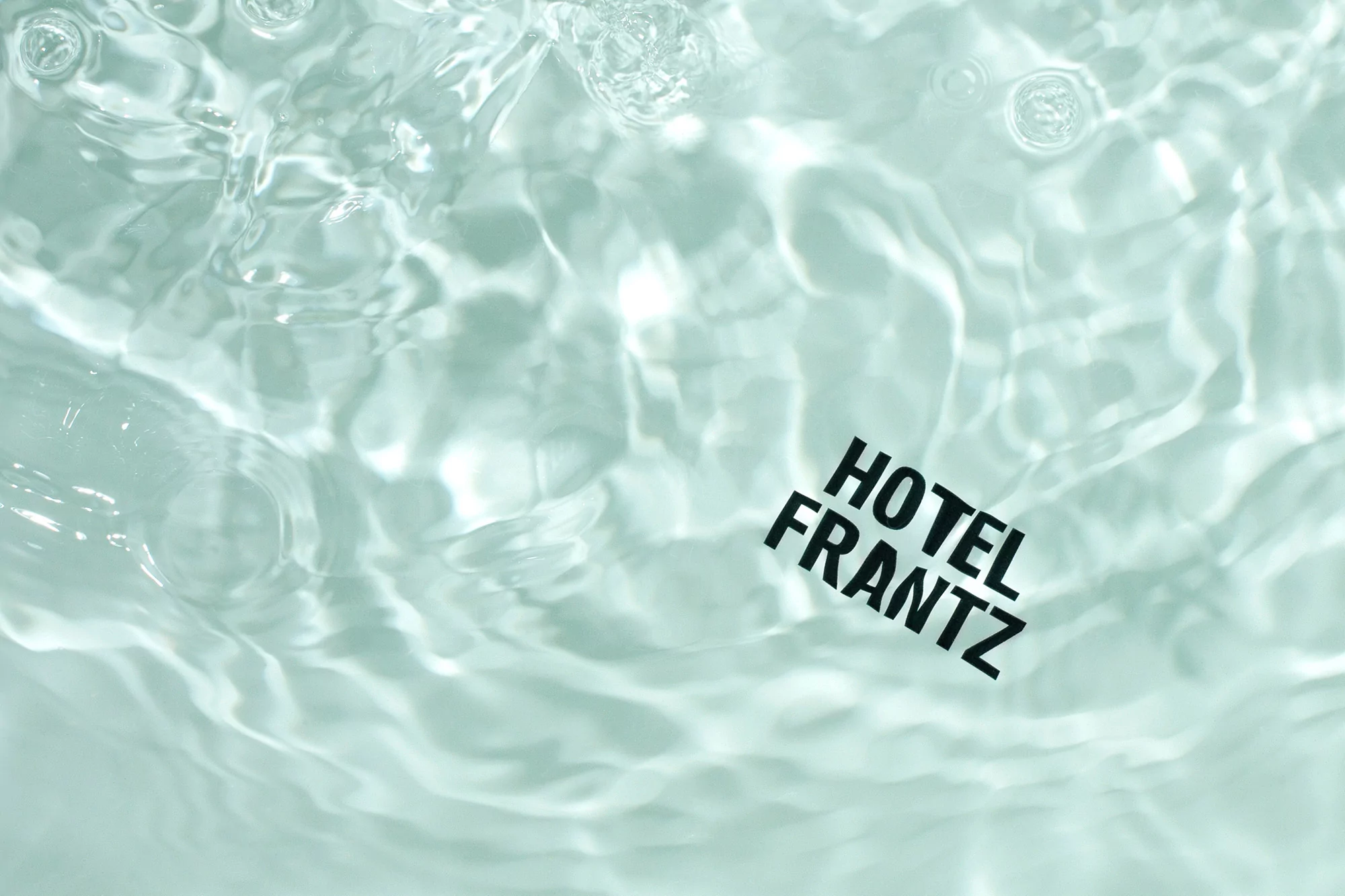 Water surface with light reflections and the text 'Hotel Frantz' floating on a card in the lower right corner.