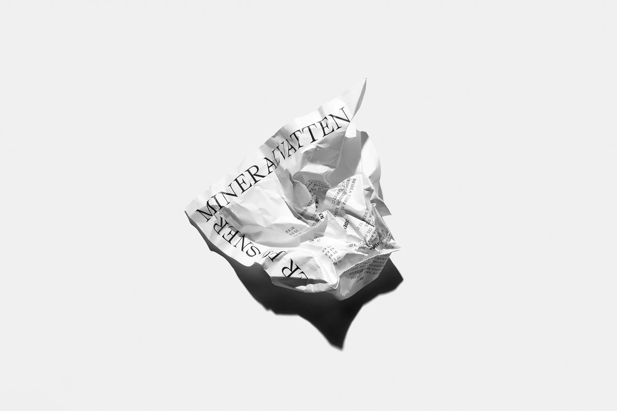 A crumpled white paper ball with black text on a white background, creating a minimalist and abstract graphic design.