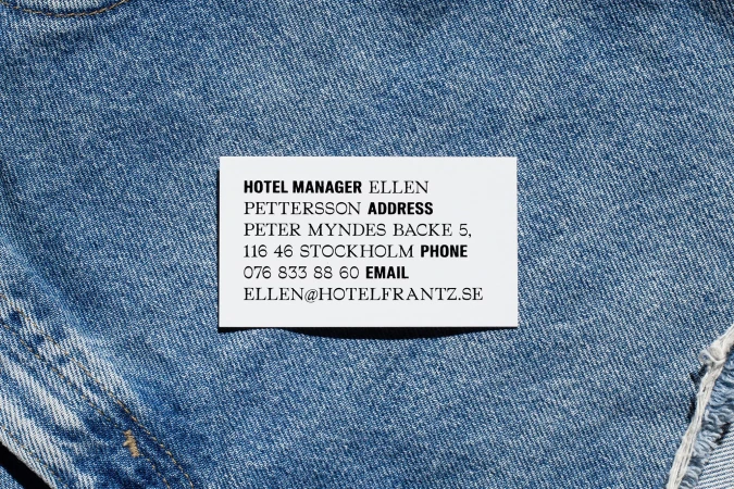 White business card with black typography placed on textured blue denim fabric for Hotel Frantz brand identity design.