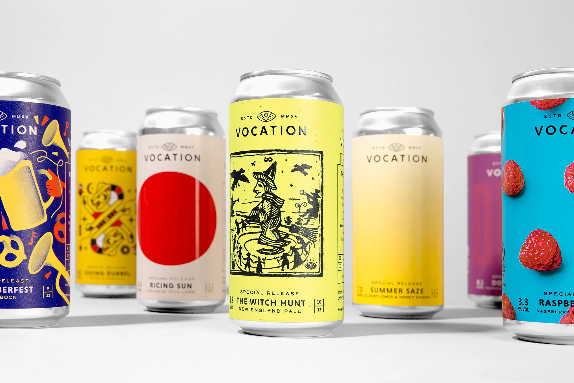 Several aluminum cans of Vocation beer are lined up, each with unique label designs featuring illustrations and vibrant colors, against a white backdrop.