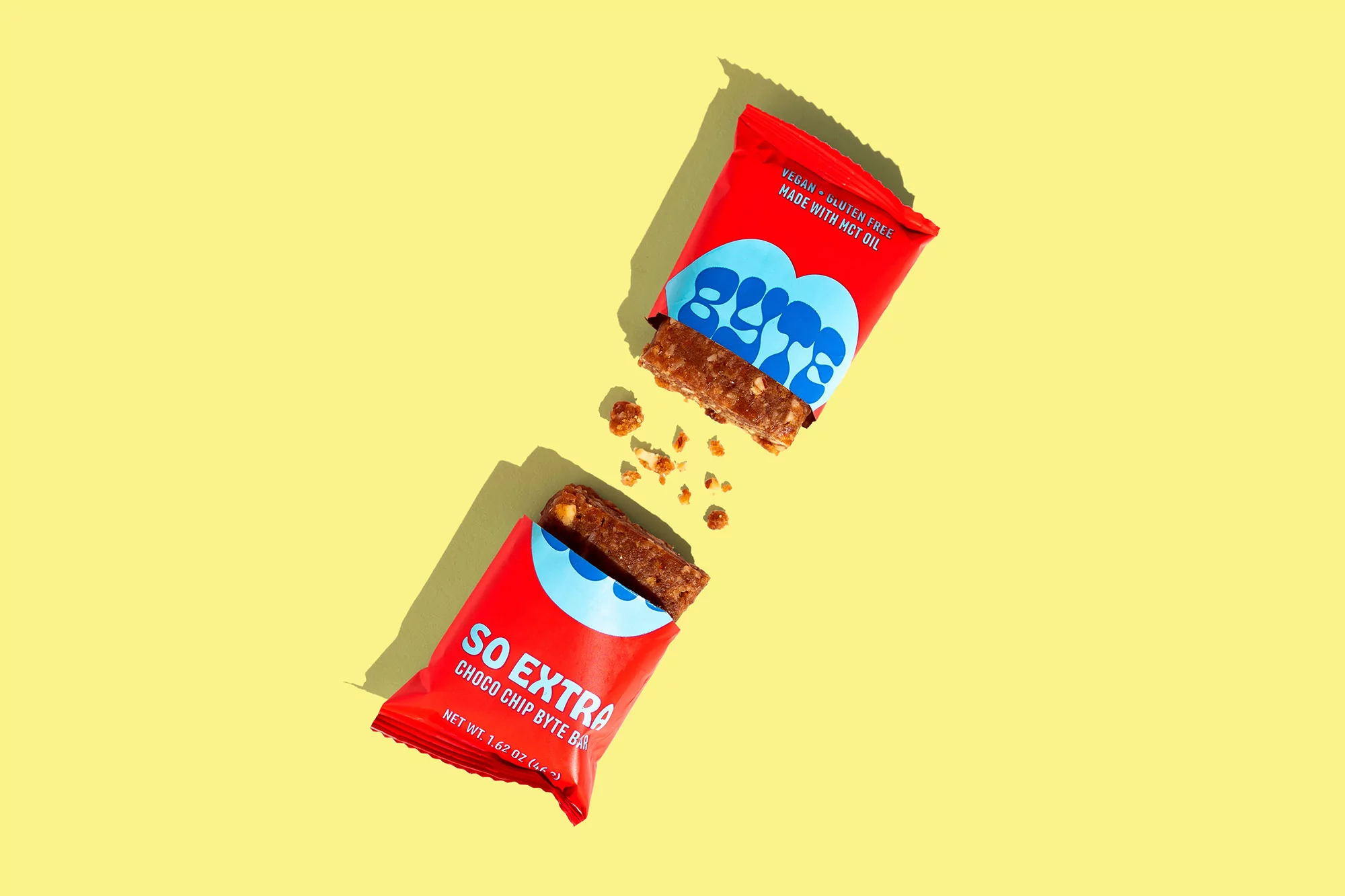 Overhead shot of two opened chocolate chip snack bars in red wrappers on a yellow background. Vegan, gluten-free food product.