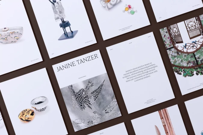 Several printed artworks are displayed on a dark brown surface, showcasing jewelry, sculpture, silversmithing, and stained glass art.