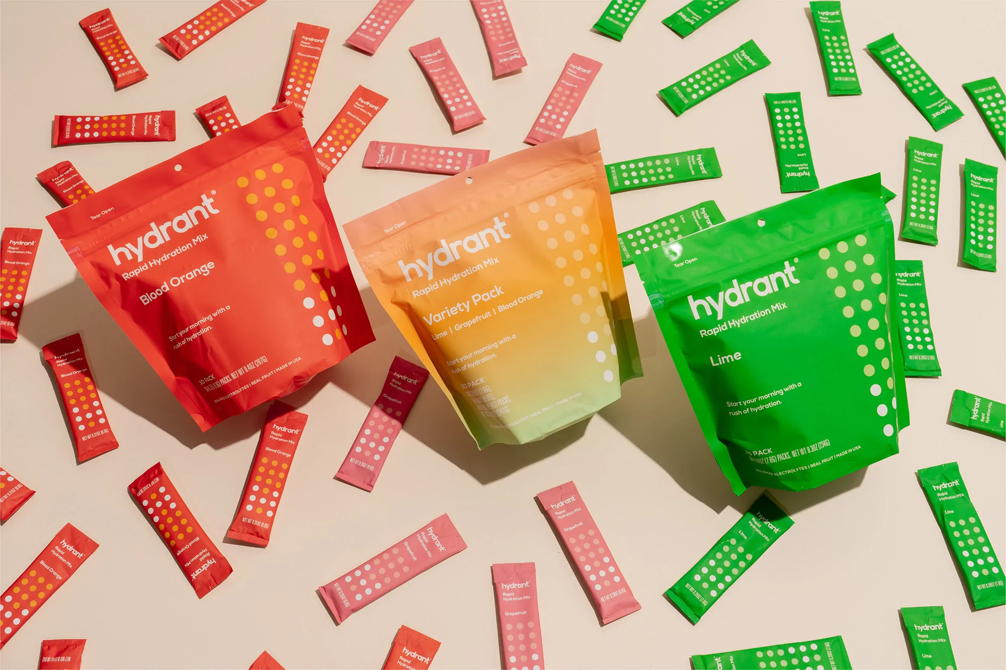 Three Hydrant Rapid Hydration Mix packs in blood orange, variety pack, and lime flavors with scattered individual packets.