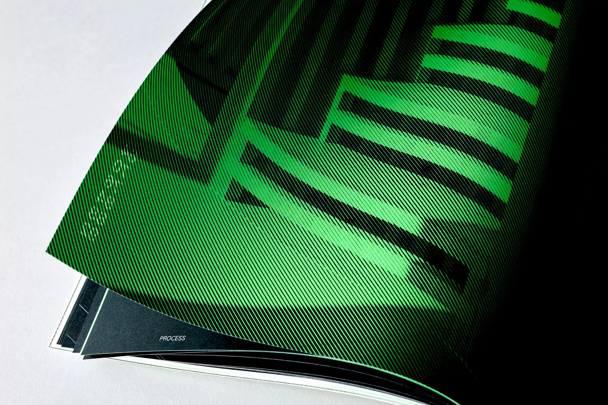Abstract graphic art featuring diagonal stripes in shades of green and black, showcased within the pages of a printed magazine.