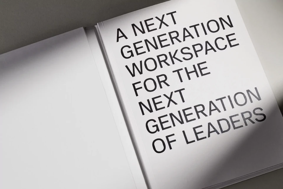 Opened book featuring the text 'A Next Generation Workspace For The Next Generation of Leaders' in black font on a white page.