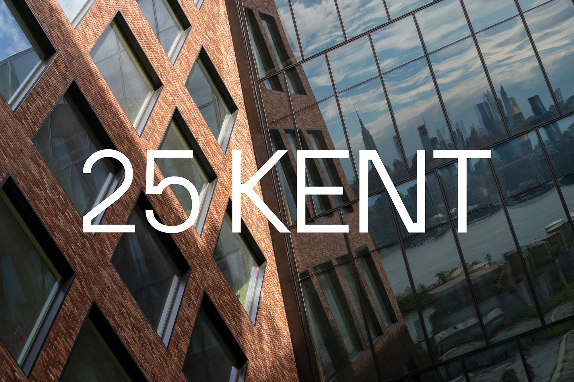 Exterior architecture shot of 25 Kent building featuring brick facade and glass windows with a city skyline reflection, daytime.