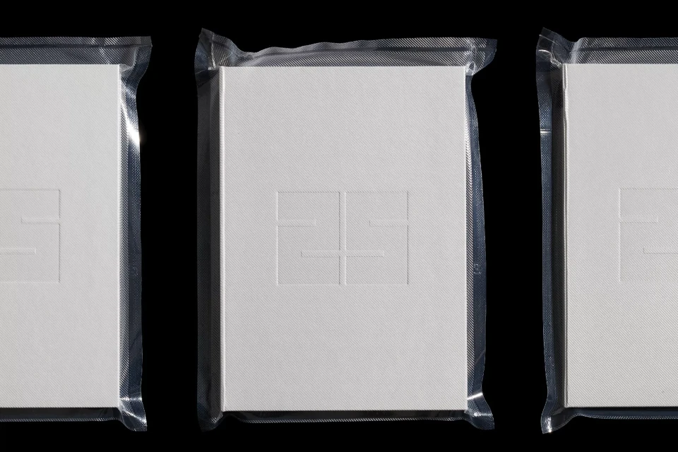 Three packaged white books are precisely arranged in a row against a dark backdrop, highlighting their clean design and textured covers.