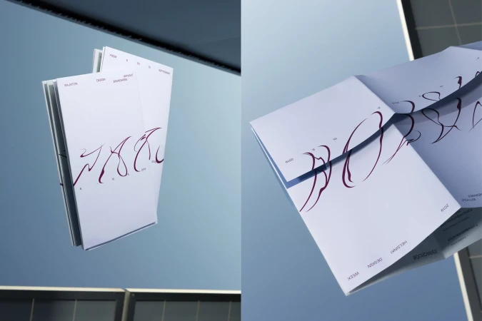 Folded printed paper booklet with dark red custom typography against a pale blue sky and dark architectural frame