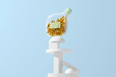 Clear glass bottle filled with golden capsules resting on white geometric pedestals against a light blue backdrop.