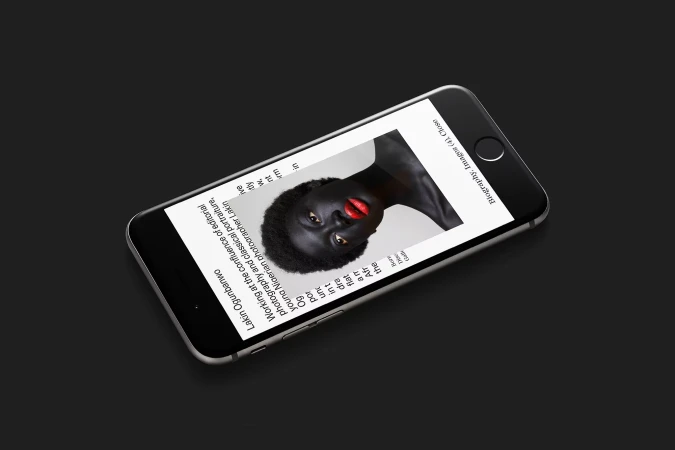 Editorial portrait of an African female model with red lipstick shown on the screen of a black mobile phone against a black background.