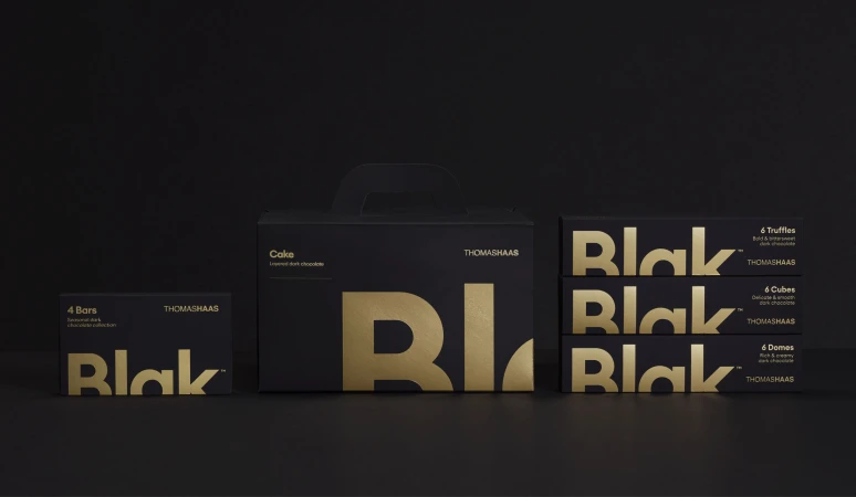 Black and gold chocolate boxes by THOMASHASS featuring the 'Blak' brand displayed in a studio setting against a dark background.