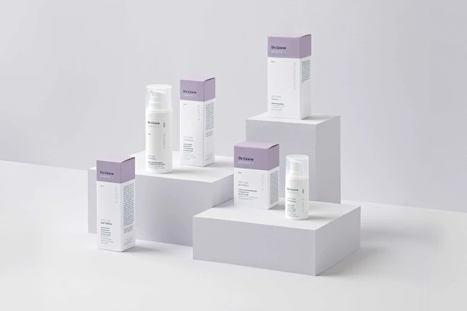 Cosmetic product line by De Grove featuring anti-age serum and hydration on a white platform with lavender and white packaging.