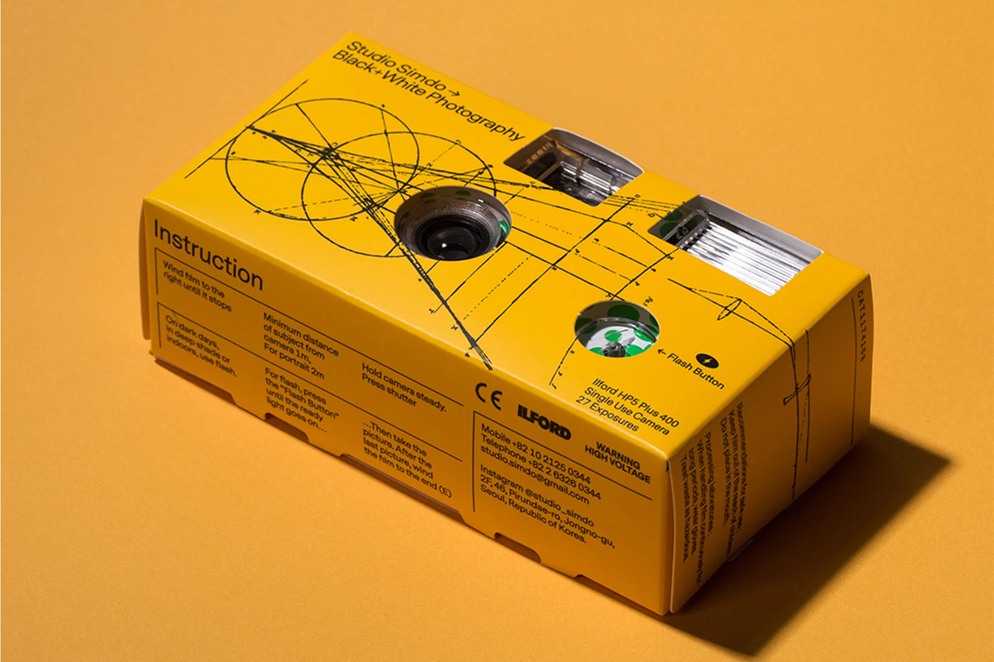 Studio Simdo black and white photography single use camera on yellow background. Camera box features geometric design and text.