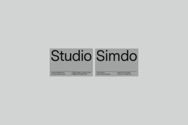 Two minimalist business cards with black typography on a solid grey background for Studio Simdo brand identity.