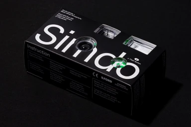 Black single-use camera box with white typography resting on a dark background.