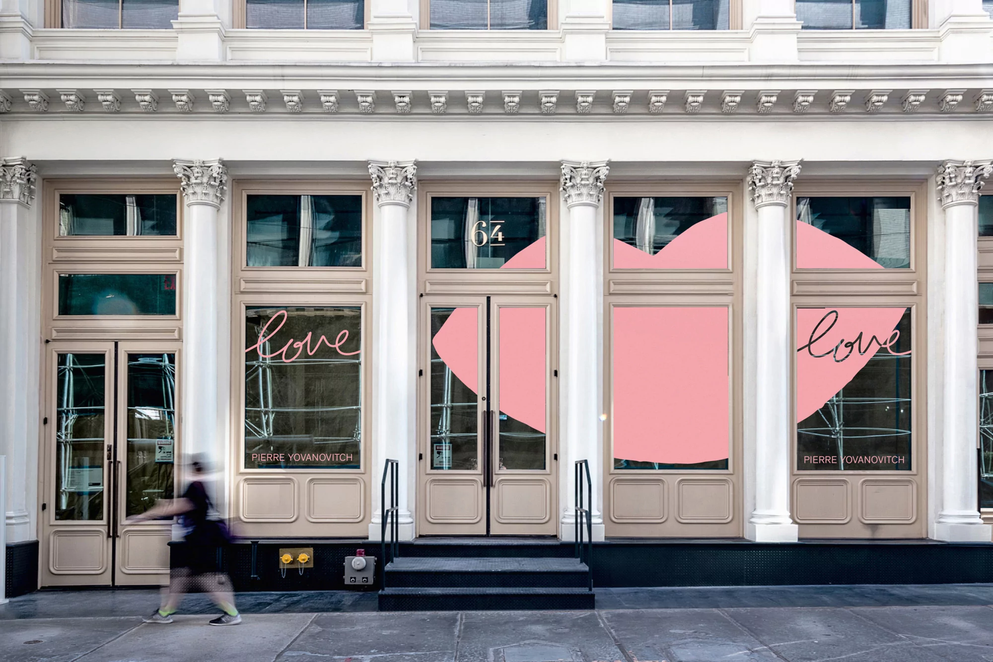 Storefront facade with modern design elements, pink heart accents, and a blurred pedestrian passing by in an urban environment.