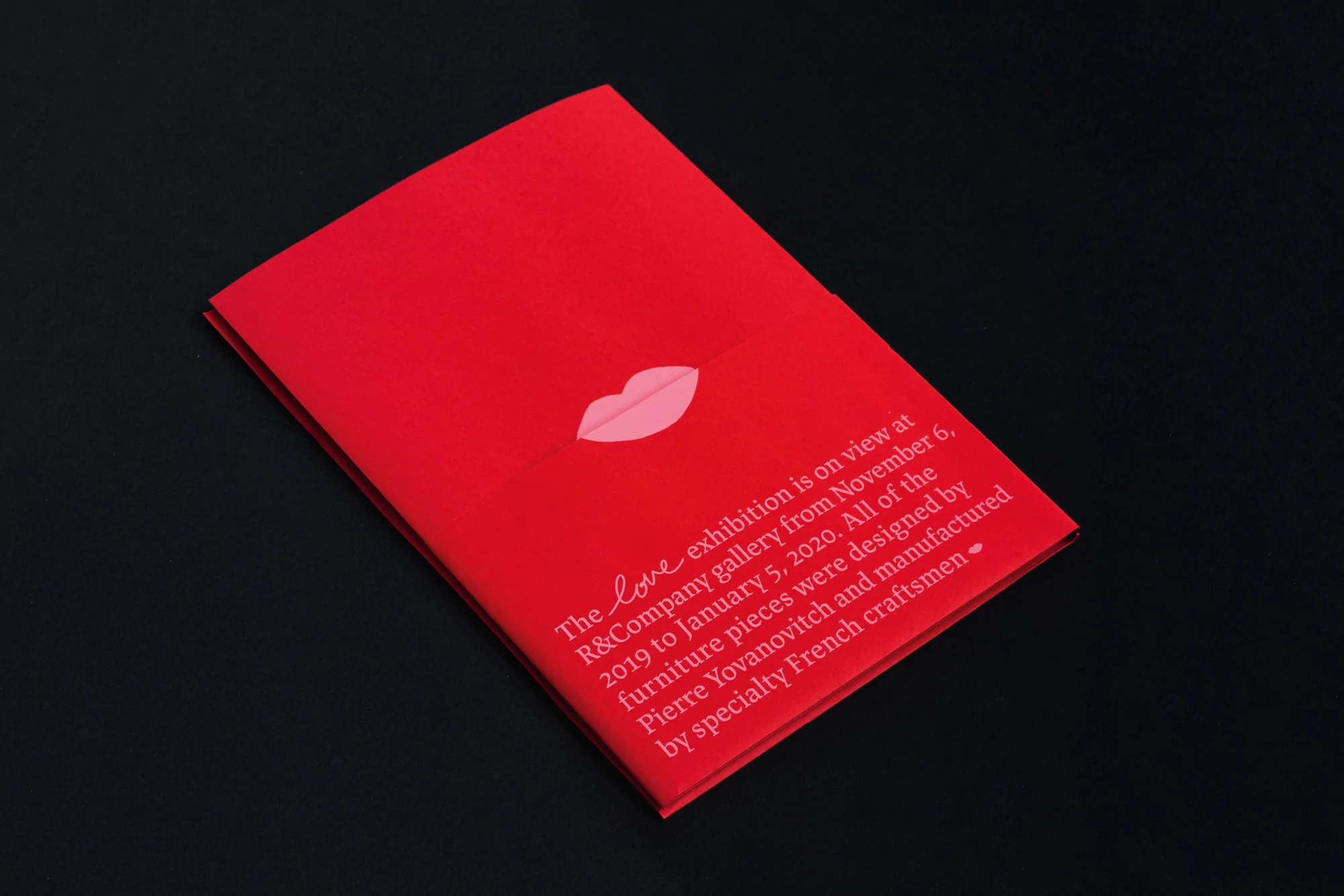 Red exhibition brochure featuring lip icon and event information. Advertising furniture exhibition designed by Pierre Yovanovitch.