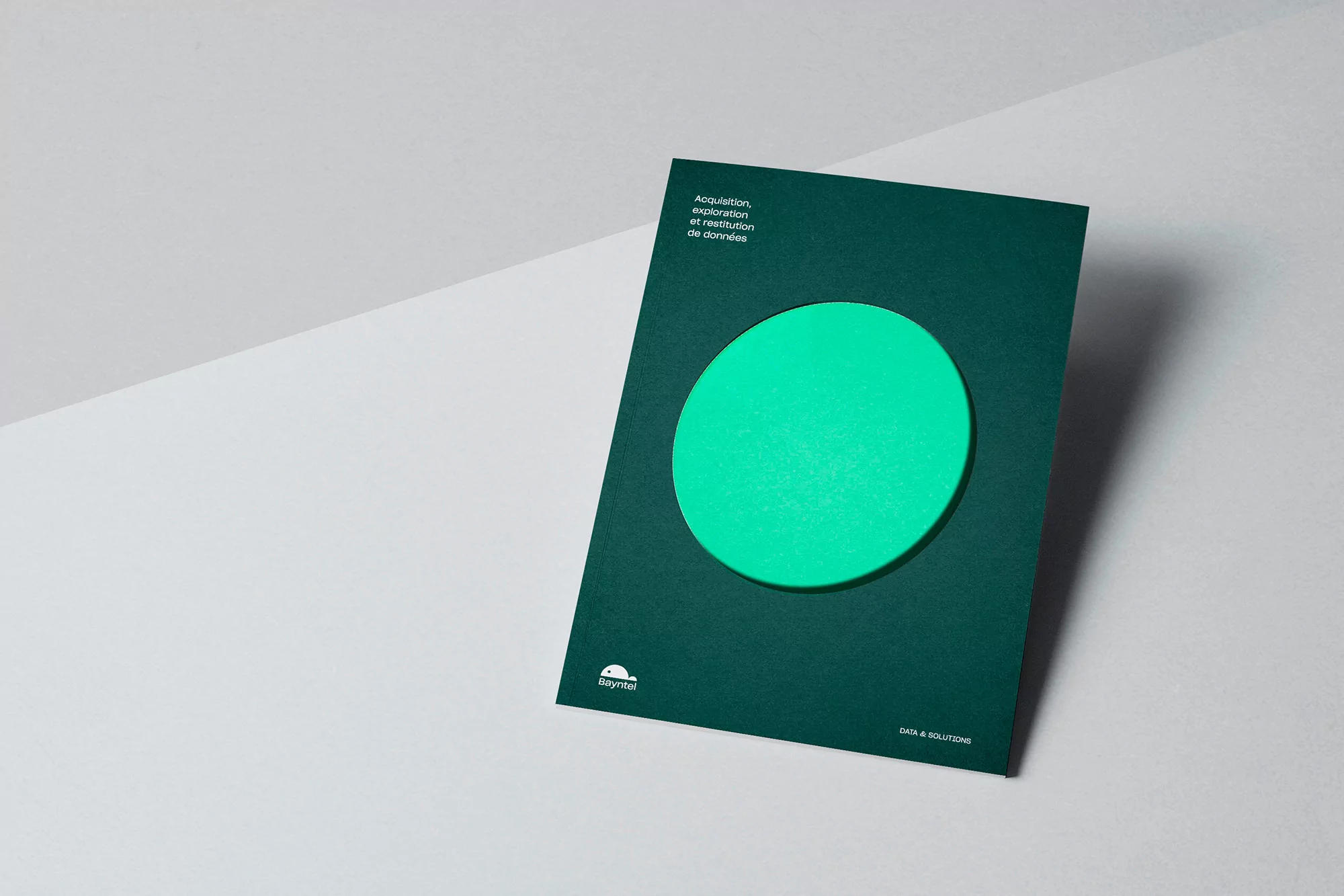 Close-up of a dark green booklet with a bright green circle, featuring the text 'Acquisition, exploration et restitution de donnees'.