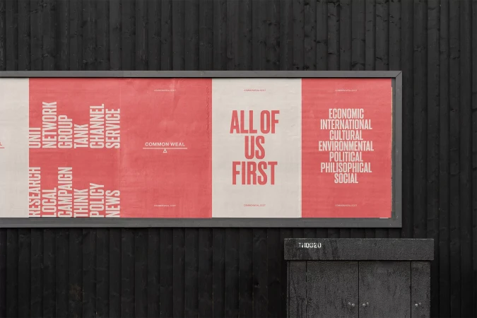 Public art installation featuring three panels with typographic designs in red and white on a black wall, promoting social and political themes.