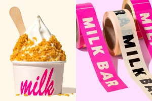 Soft serve ice cream topped with cornflake crunch in a branded cup next to rolls of pink and white branded tape.
