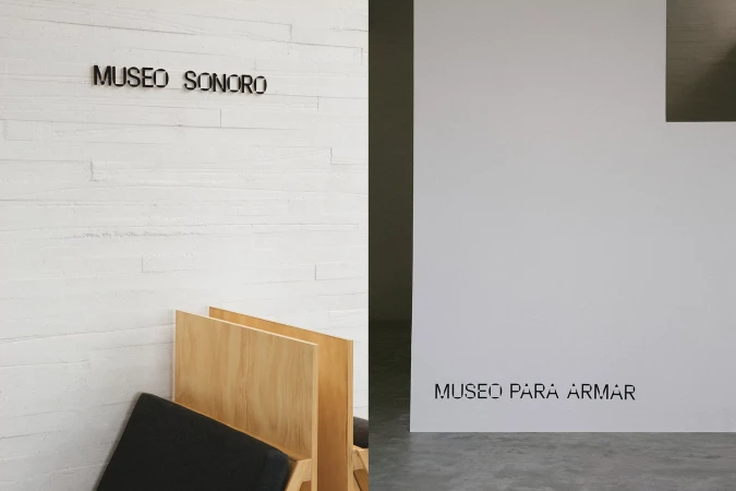Interior architectural view displaying white brick texture, wooden furniture, and clean typography signage.