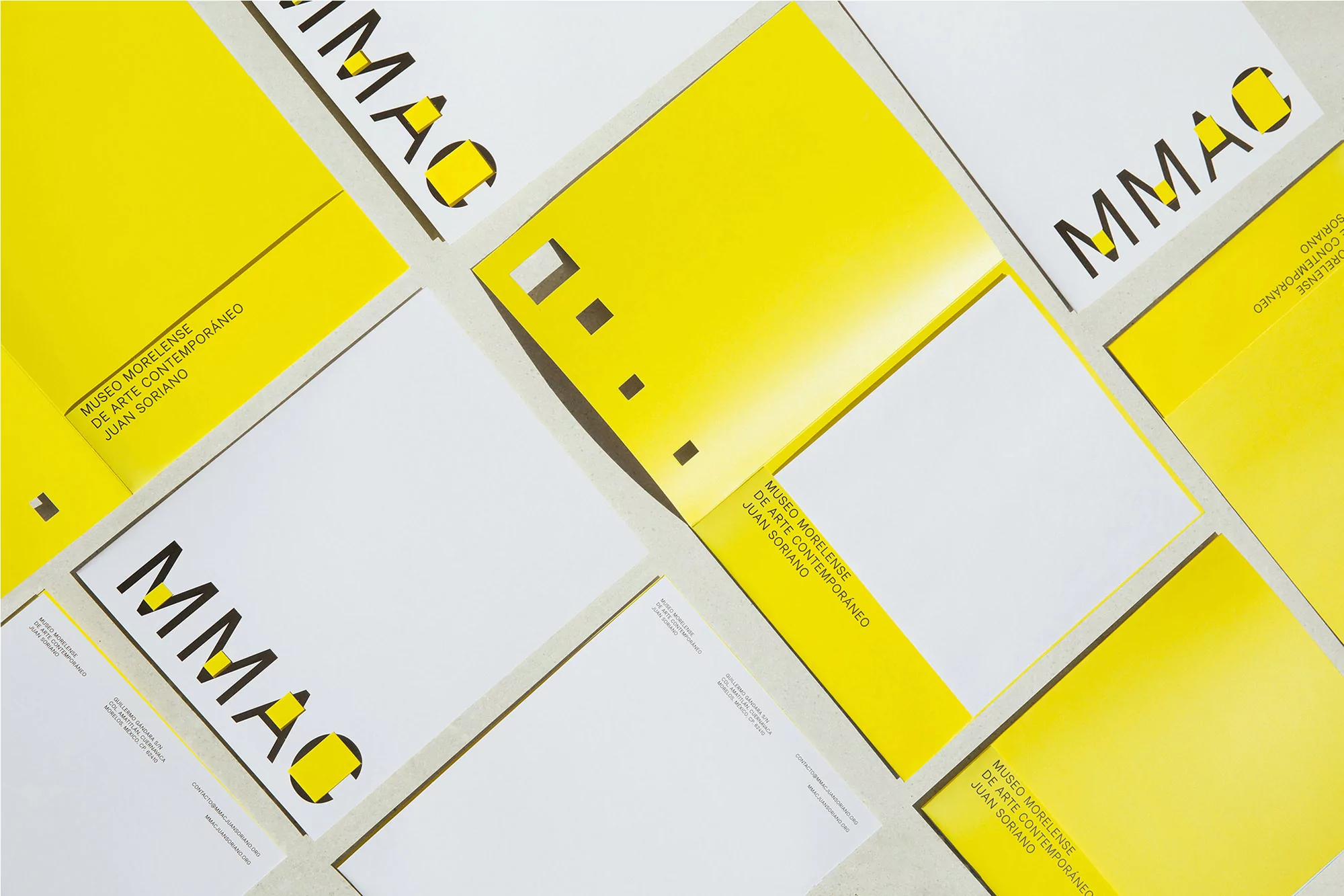 Overhead shot of yellow and white paper materials with geometric shapes and modern text spelling out MMAC and Museo Morelense.