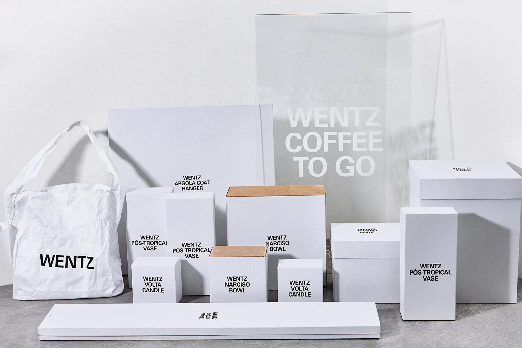 Wentz brand display featuring a collection of white product packaging, including boxes, a tote bag, and a transparent sign.