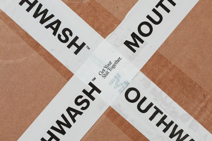Cardboard box sealed with white branded tape displaying the word Mouthwash in bold black lettering