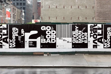 Black and white typography posters pasted on an urban construction wall featuring bold contrasting lettering and quotes.