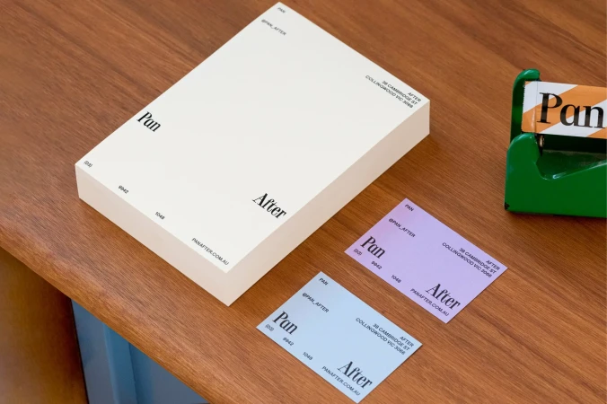 Pan After brand stationery set including a white box and purple and blue business cards on a wooden surface