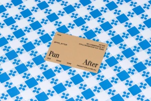 Brown business card for Pan After placed on top of a blue and white patterned paper surface