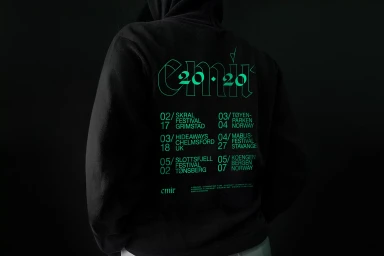 Person wearing a black hoodie with green graphic text on the back against a black background
