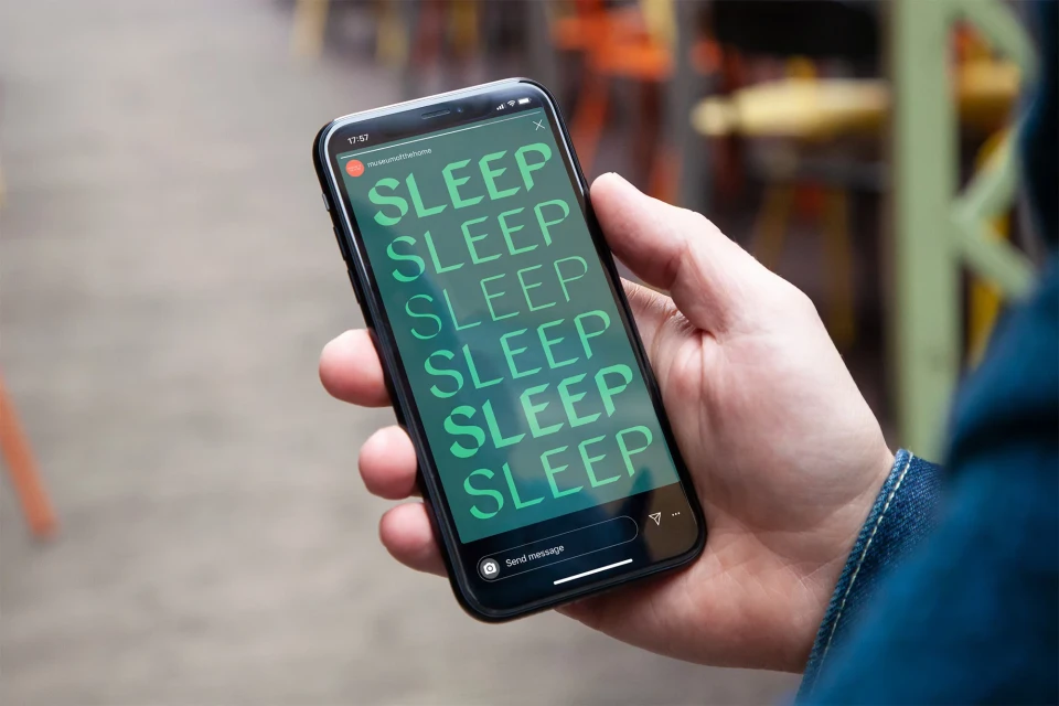 Close-up of hand holding smartphone displaying the word 'SLEEP' in stacked green text on the screen.