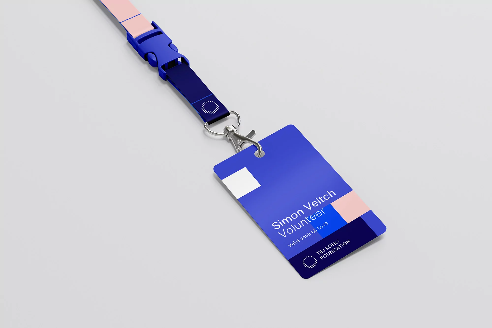 ID badge on a lanyard. The badge is blue with white text, 'Simon Veitch Volunteer' and a logo for TEJ KOHLI FOUNDATION.