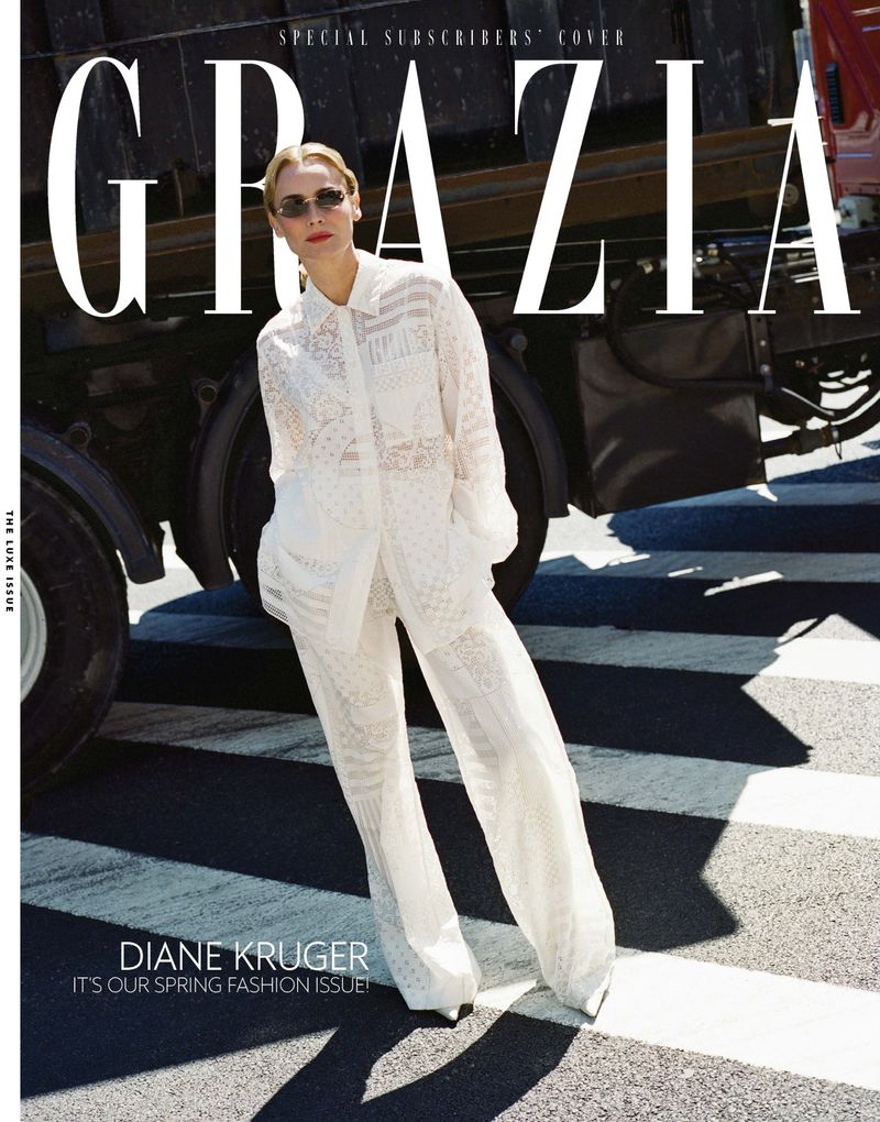 A woman in a white lace outfit and sunglasses poses for a fashion magazine cover on an urban street.