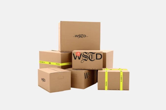 Stack of branded cardboard boxes with a logo and neon yellow tape isolated on a white background, shot in a photo studio.