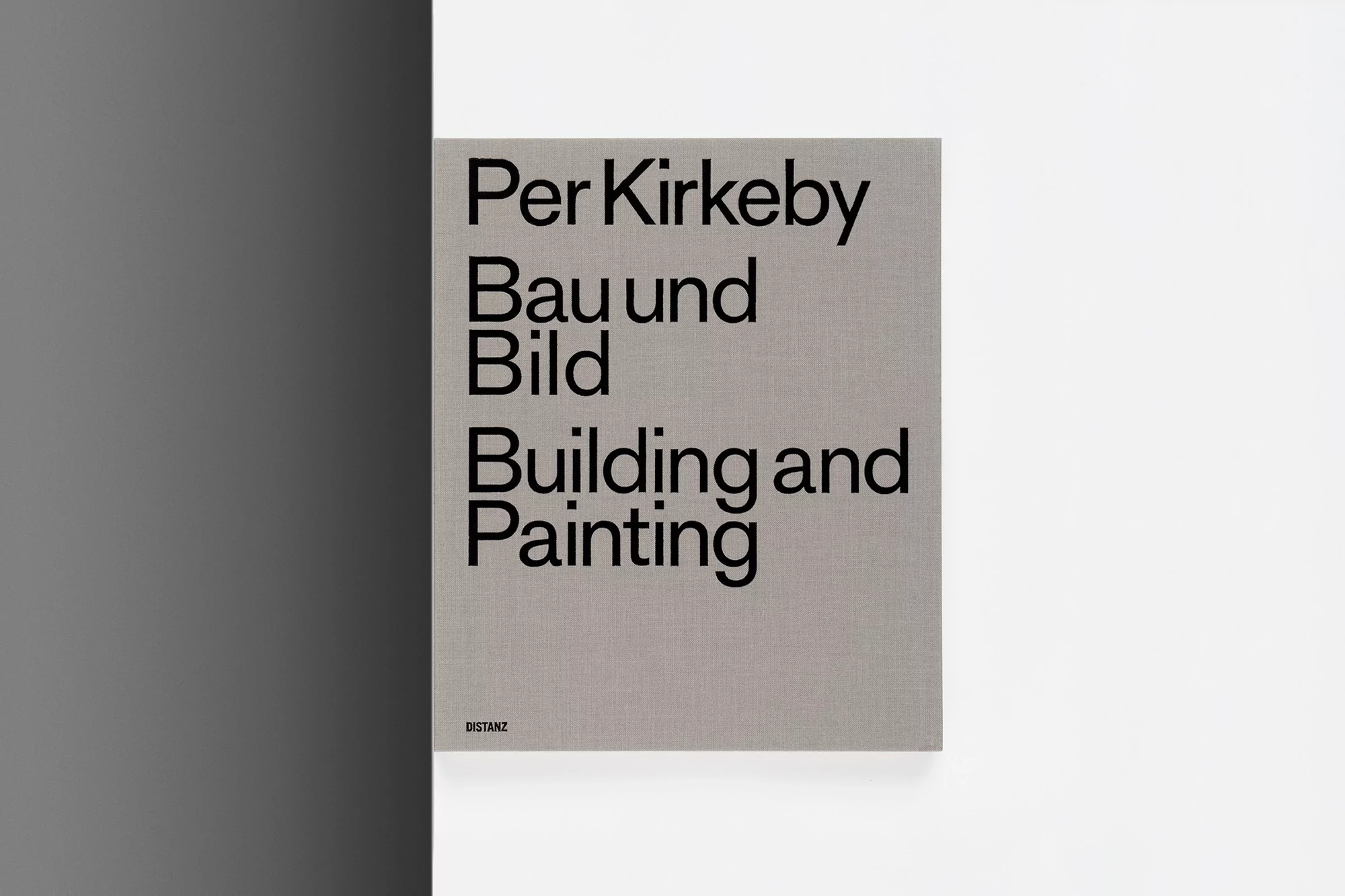 Close-up of a book cover featuring the title 'Per Kirkeby Bau und Bild Building and Painting' in bold black text on a gray textured background.