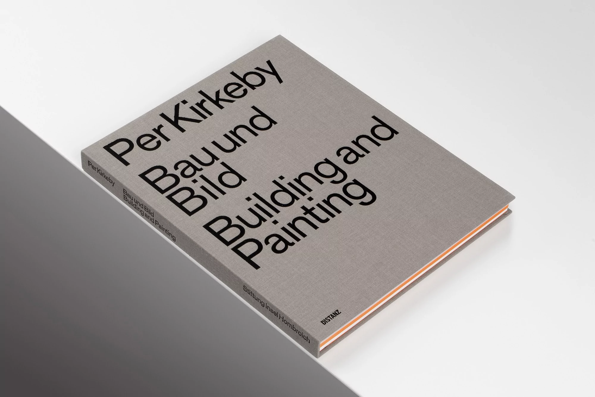 A grey hardcover book titled Per Kirkeby Bau und Bild Building and Painting resting on a split white and dark grey surface