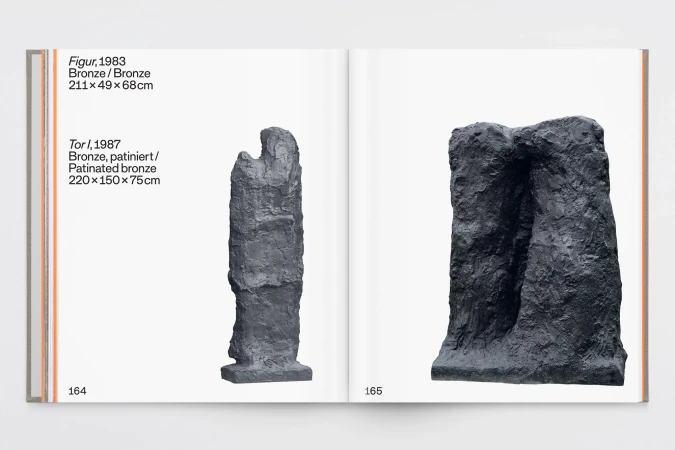 Open book showcasing two dark-colored, textured abstract bronze sculptures on white pages. The book lies open on a neutral surface.