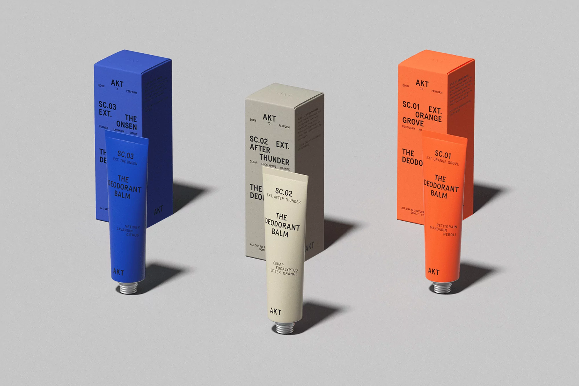 AKT deodorant balms and boxes in blue, beige, and orange on a white surface with minimalist design and clear product labeling.