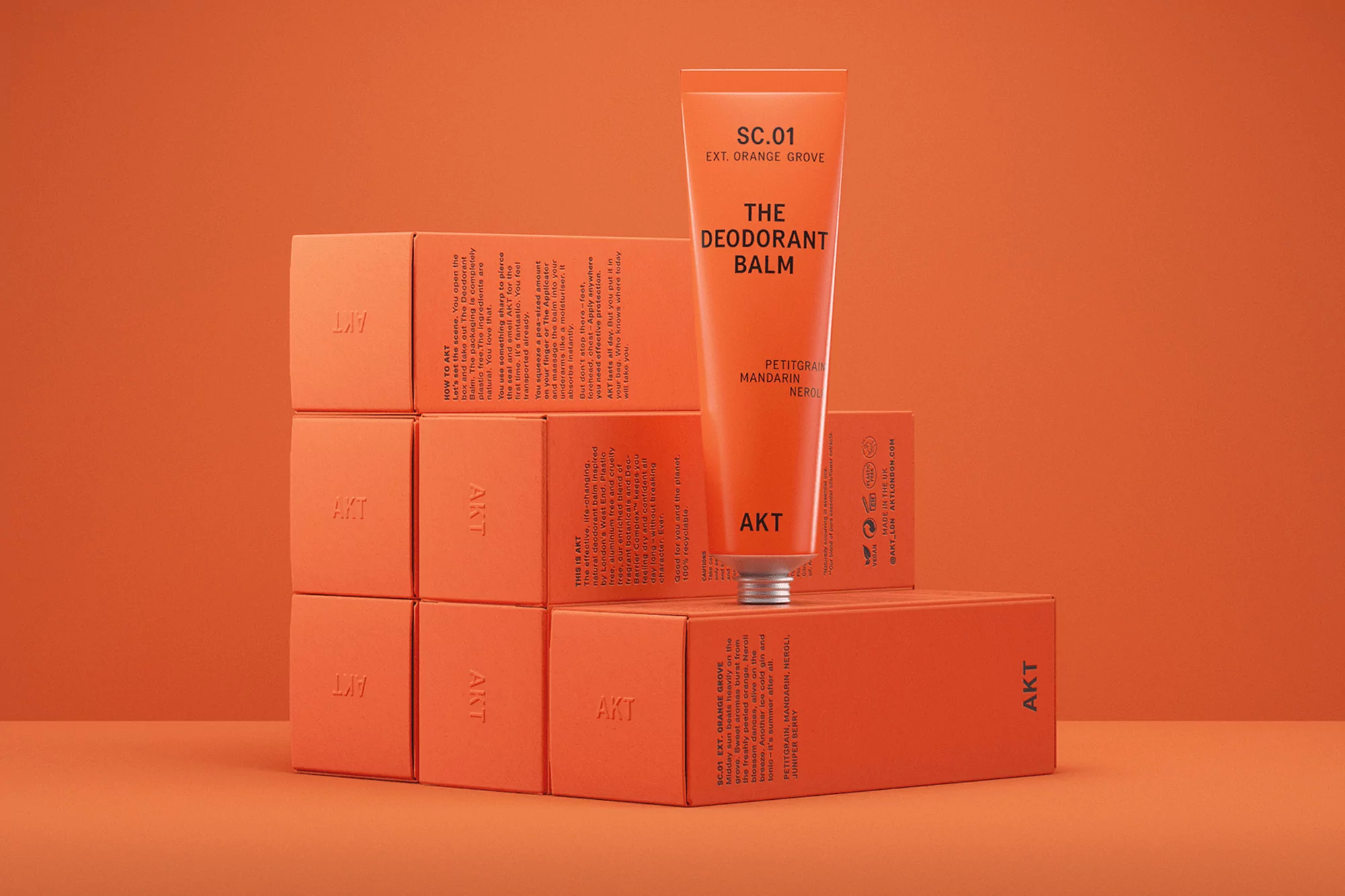 Cosmetic product shot: Orange tube of deodorant balm on an orange background with stacked orange boxes. Beauty product.