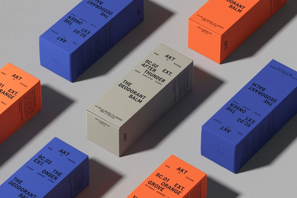 Colorful AKT deodorant balm boxes arranged on a gray surface, showcasing various scents and packaging design details, and branding.