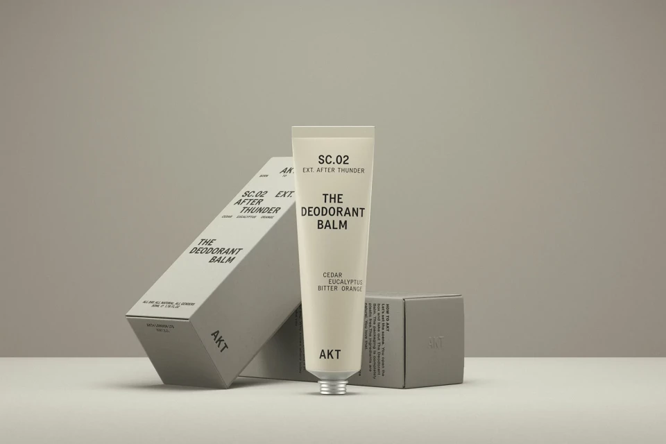 AKT deodorant balm and packaging featuring minimalist design and neutral color palette on a neutral background, product photography.