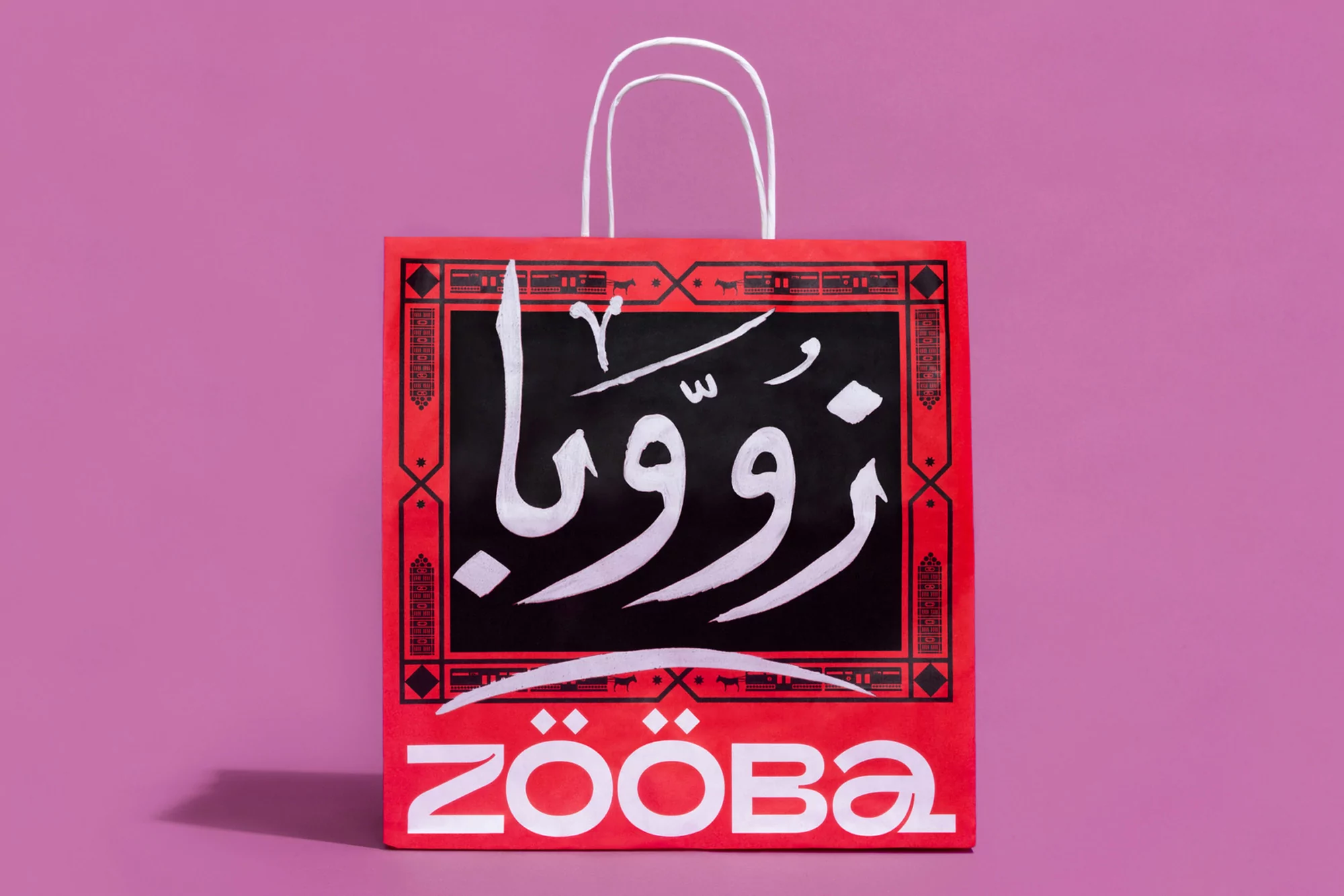 Brightly lit shopping bag with black and white Arabic and English text designs, featuring a distinctive red color scheme and handle.