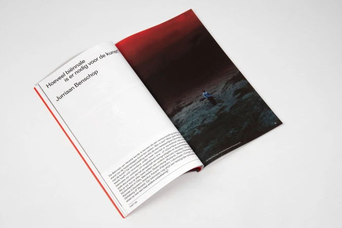 Open magazine features an image of a person standing on a dark, rocky landscape with a dramatic, red-toned sky. Text is visible on the opposite page.